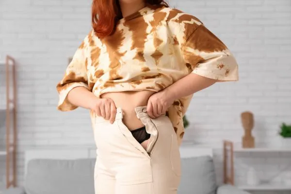 Image of woman trying to do her trousers up after pregnancy weight gain South Shields