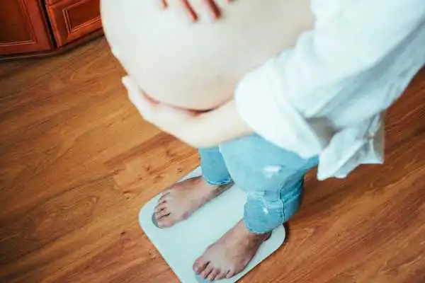 Image of woman weighing herself and experiencing weight gain through pregnancy South Shields
